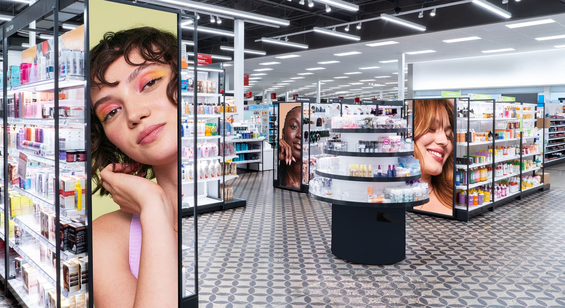 Interior of a brightly lit beauty store with shelves stocked with skincare and haircare products. Large digital screens display close-up portraits of diverse women with makeup, integrated into the aisles. The floor has a patterned tile design.