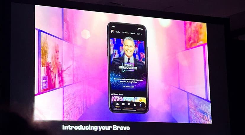 Alt text: A presentation slide displaying a smartphone screen featuring the "Your BRAVOVERSE" app interface with a man in a suit smiling, surrounded by a colorful, abstract purple and pink background. The bottom text reads "Introducing your Bravo."