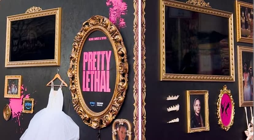 Ornate gold picture frames of various sizes arranged on a dark wall, with one large oval frame containing bright pink text reading "Pretty Lethal," a white wedding dress hanging on a wooden hanger, smaller framed portraits, two tiaras, and a pink splatter behind some frames.