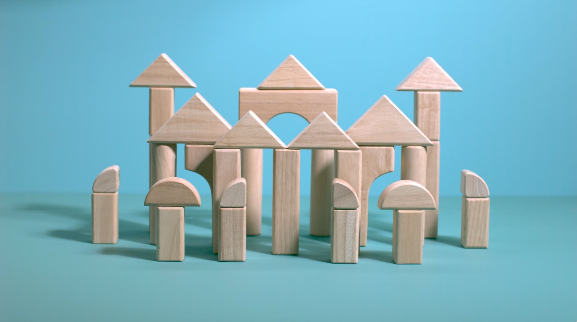 Wooden building blocks arranged to resemble a small castle or fortress against a blue background.