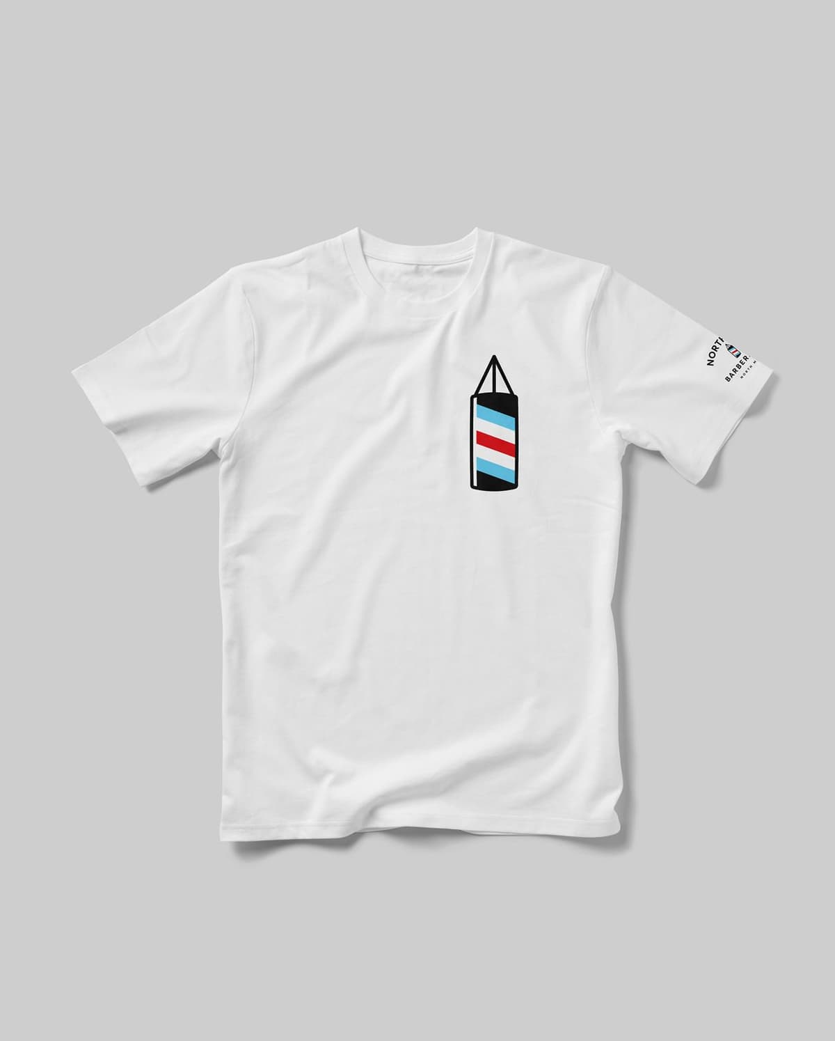 White T-shirt with a small graphic of a hanging barber pole with blue, red, and white stripes on the left chest area and a matching barber pole graphic with text on the right sleeve.